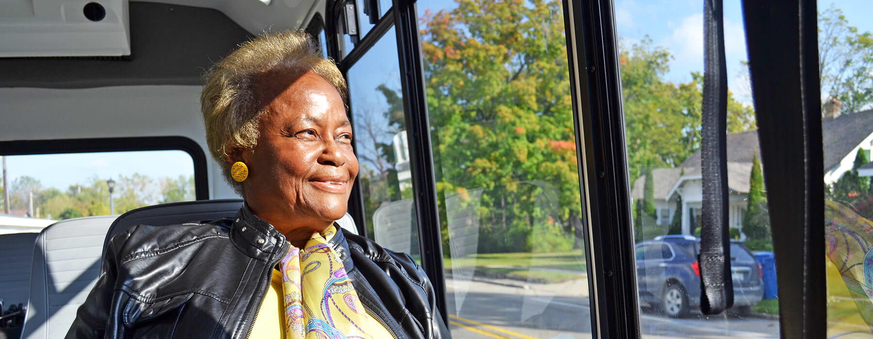 Smiling elderly woman looking out window of Your Ride bus.